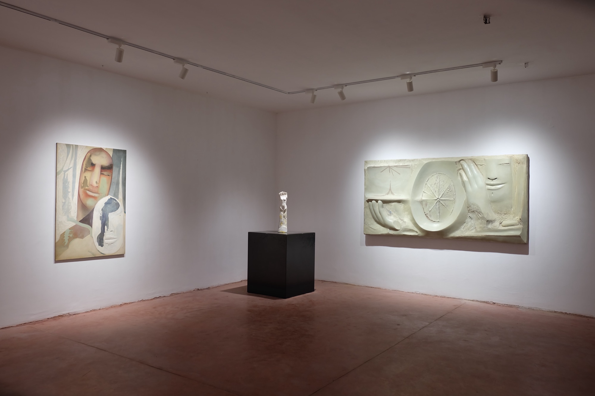 Sala con un dipinto, una piccola scultura su piedistallo nero e un rilievo in ceramica.