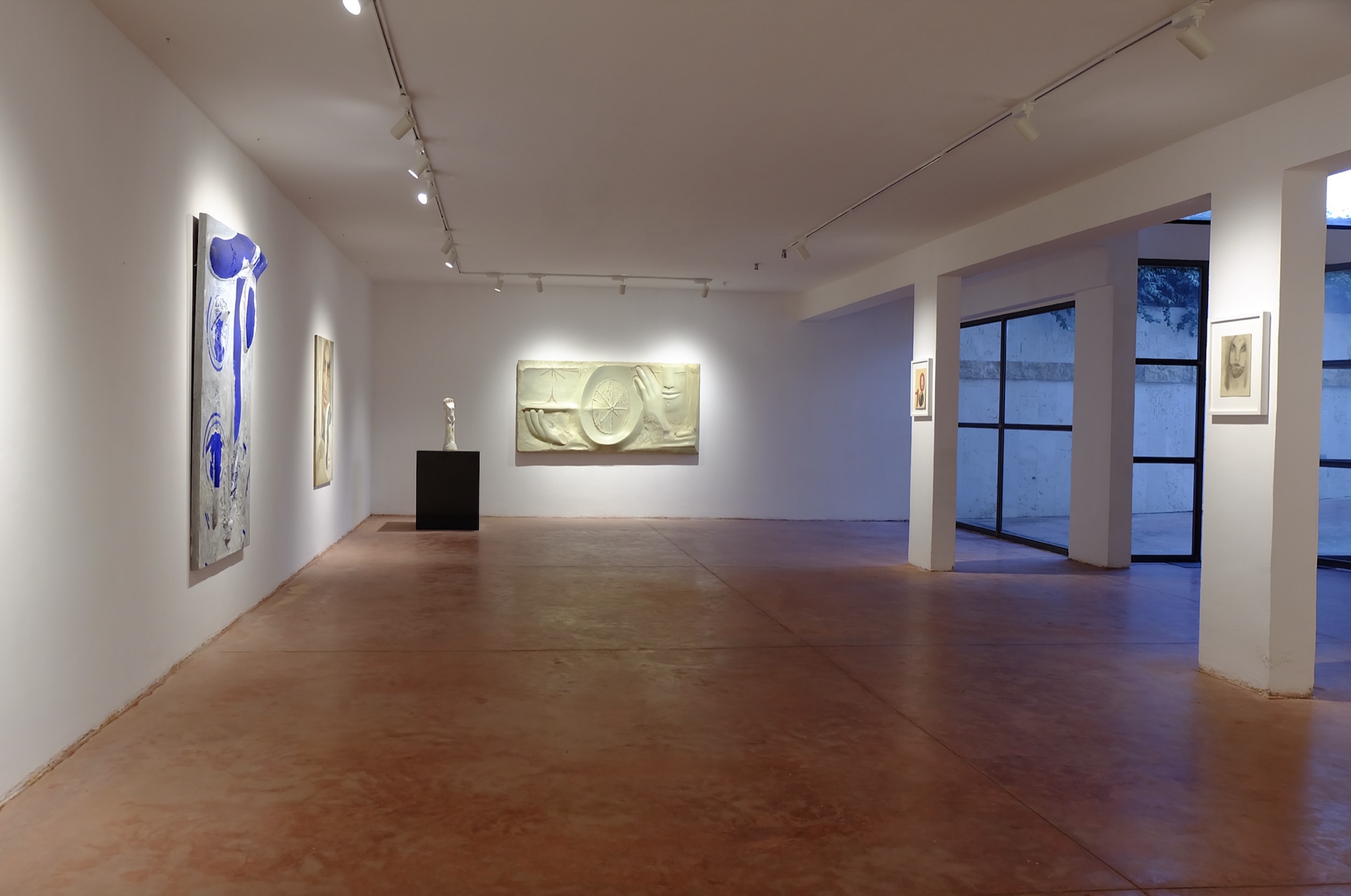 Spazio espositivo con opera blu, rilievo e ingresso luminoso sul retro.